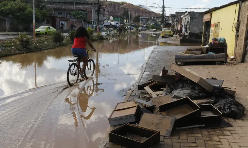 Impacto da gentrificação verde em áreas urbanas afetadas pelas mudanças climáticas, com enchentes e deterioração de infraestrutura em uma cidade brasileira.