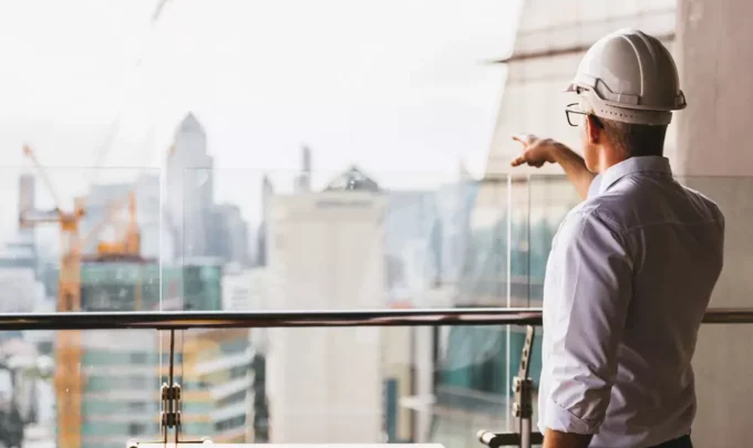 Profissional de construção civil analisando projeto de Lean Construction em um ambiente moderno de escritórios com vista para a cidade