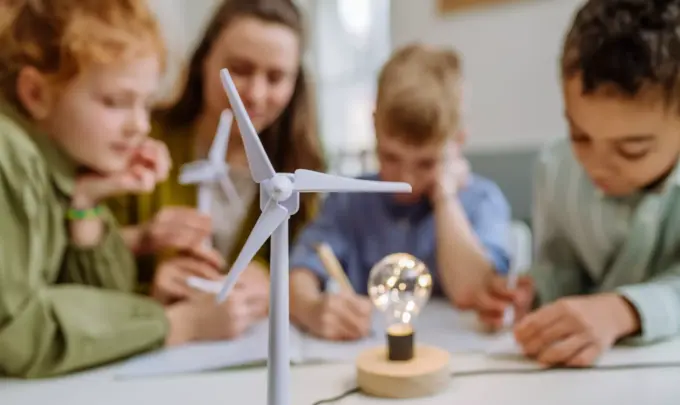 Crianças participando de uma atividade educativa sobre energias renováveis em sala de aula, com foco na adaptação climática das cidades usando fontes sustentáveis.